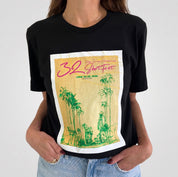 Black t-shirt with a graphic design featuring palm trees and text on a white background