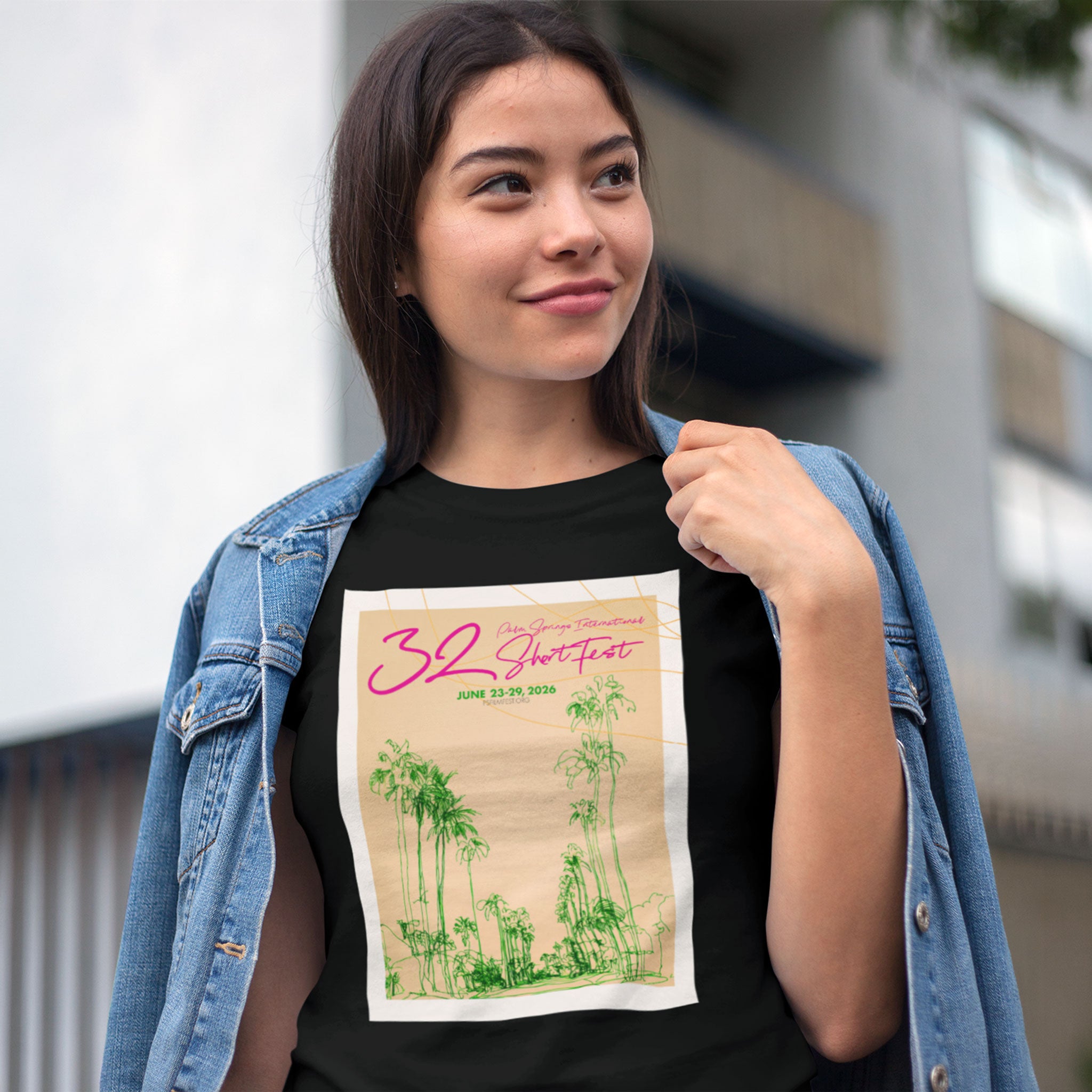 Woman wearing a black t-shirt with a graphic design, standing outdoors.