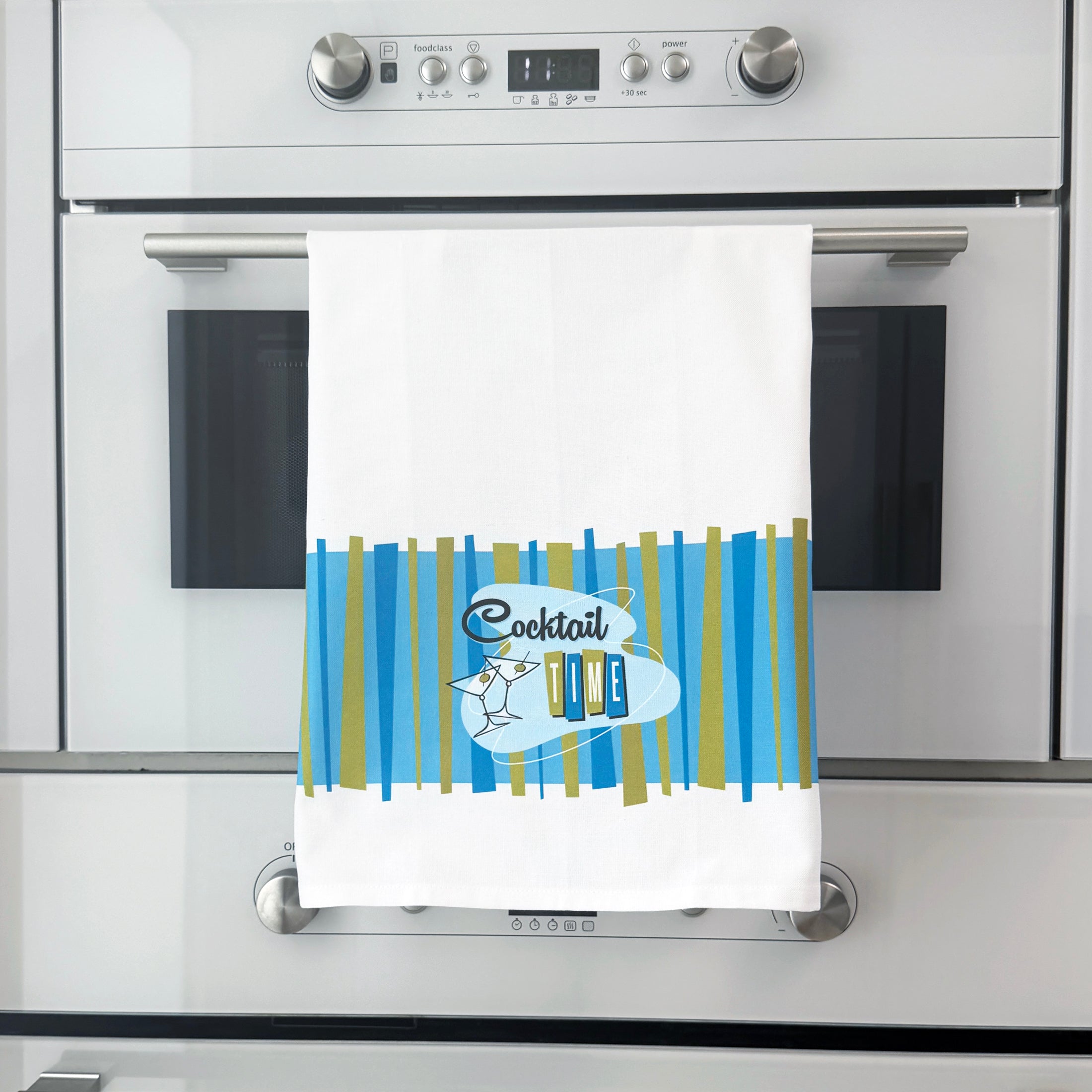 Kitchen towel with cocktail design hanging on a silver oven handle.