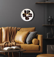 mod white wall clock with just the numbers 3, 6, 9, and 12 ahnging in a room with black wall and leather couch and various brown and black decor items