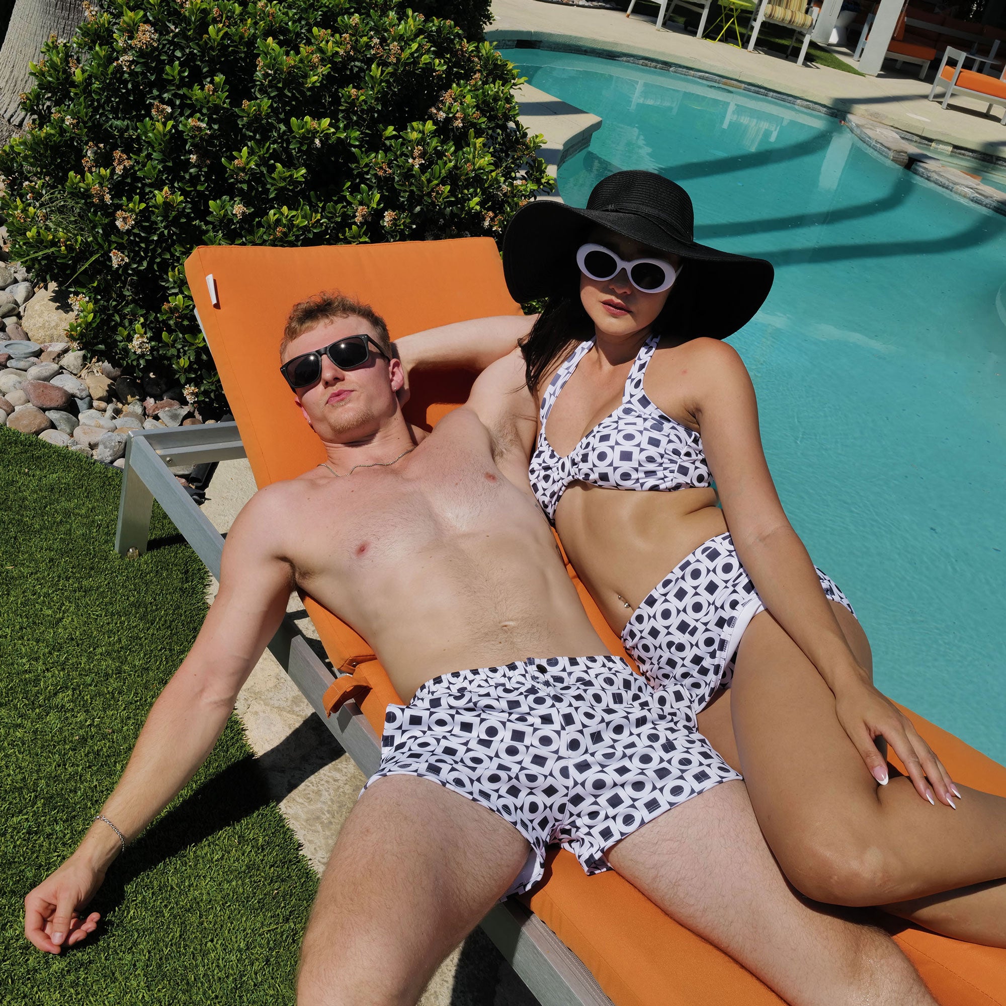 Two people in matching polka dot swimwear lounging by a pool.