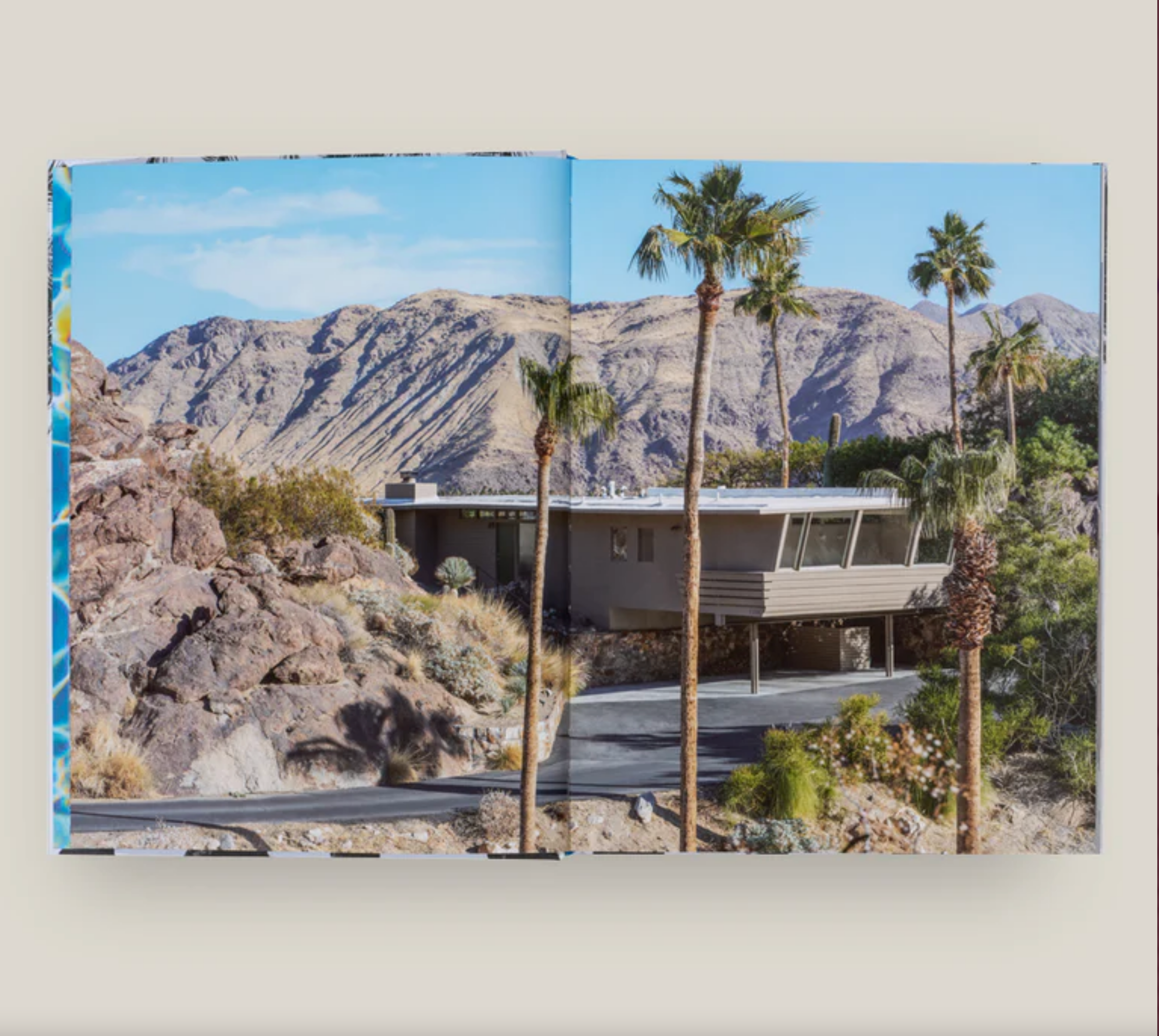 Book open to a page showing a house with palm trees and mountains in the background