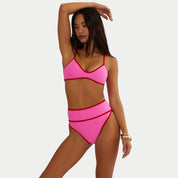 Woman wearing a pink bikini against a white background