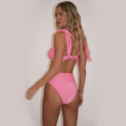 Woman wearing a pink swimsuit against a plain background