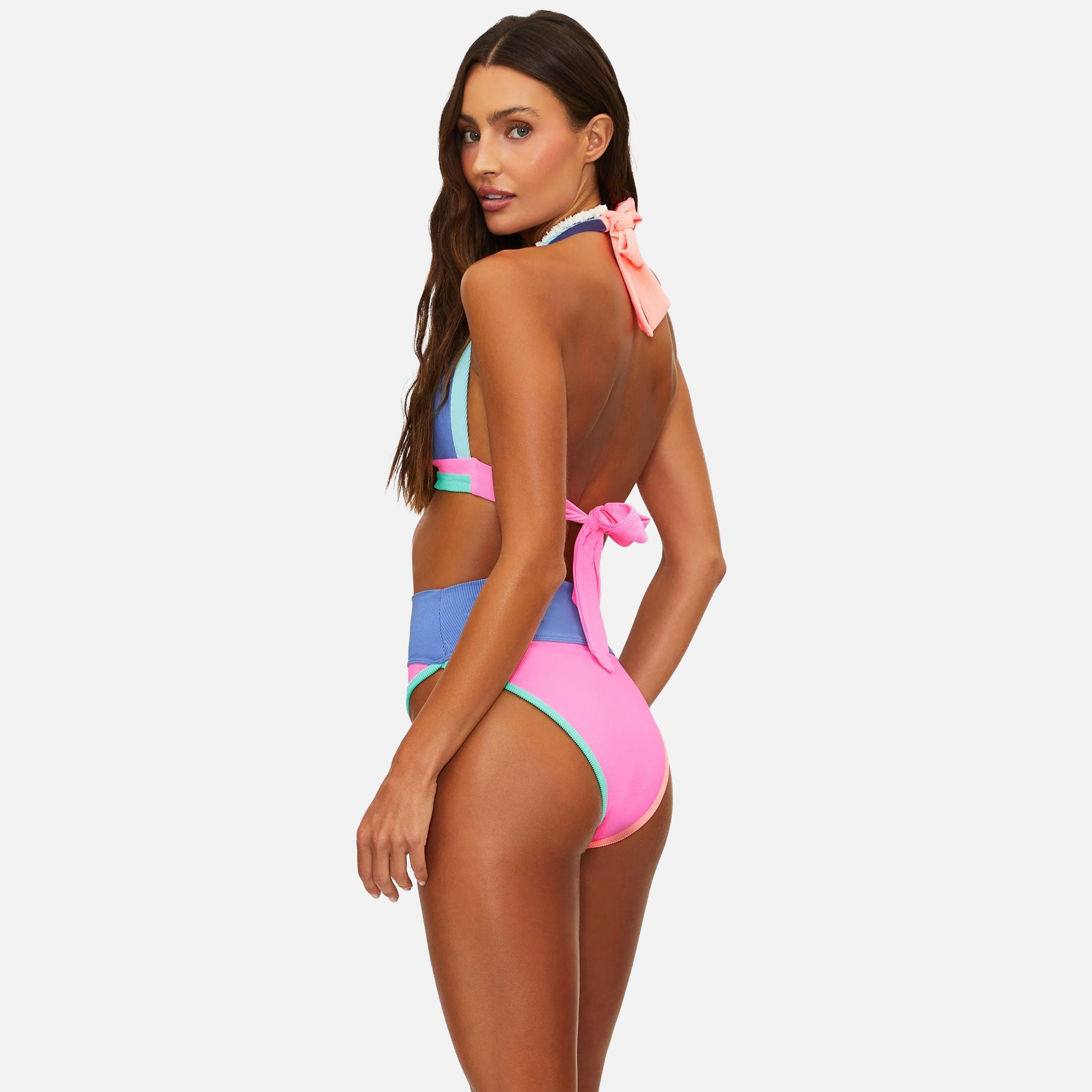 Woman wearing a colorful one-piece swimsuit with a pink bow on a white background