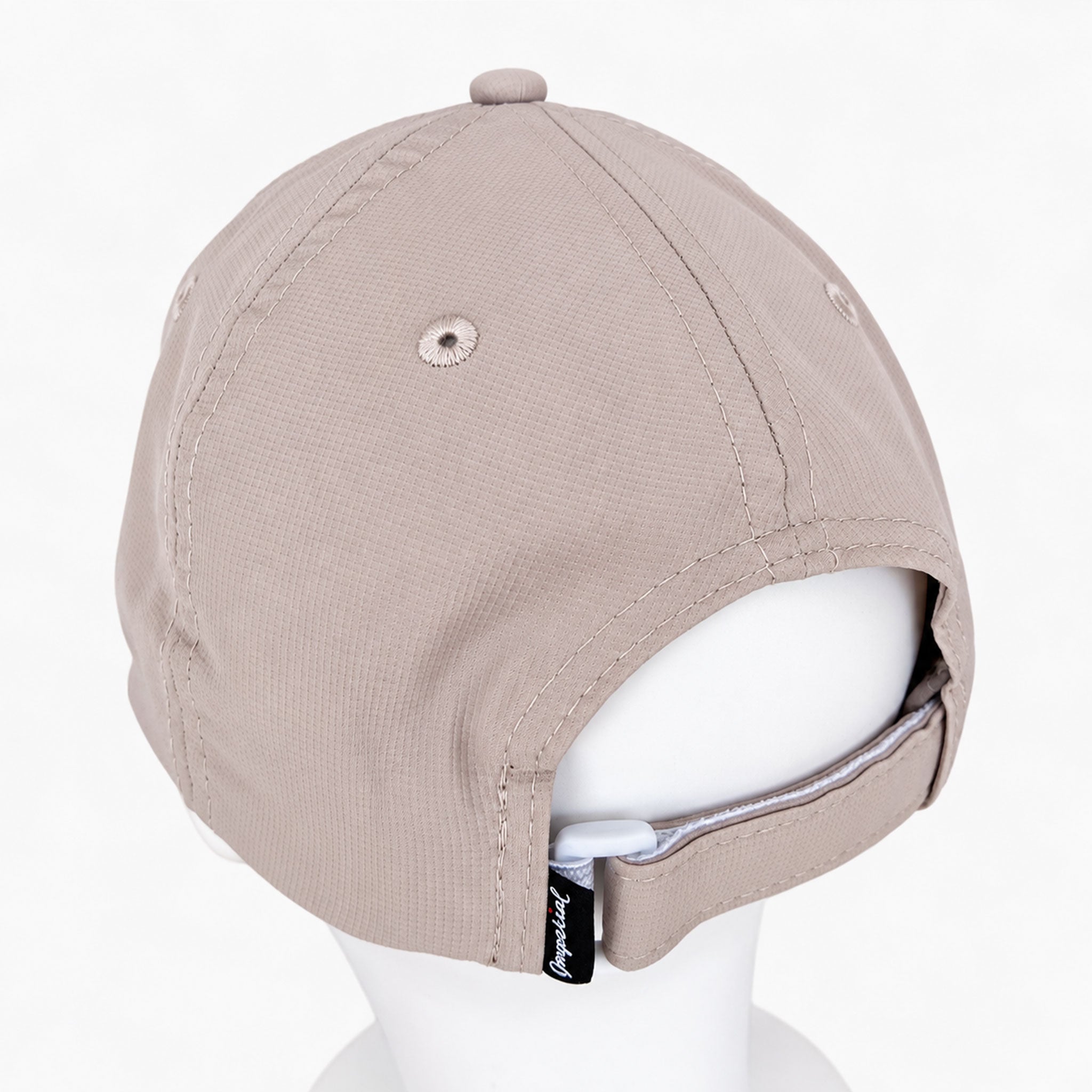 A light taupe-beige baseball cap shown from the back on a white mannequin head, featuring a rear hook-and-loop strap closure with a small black brand tag.