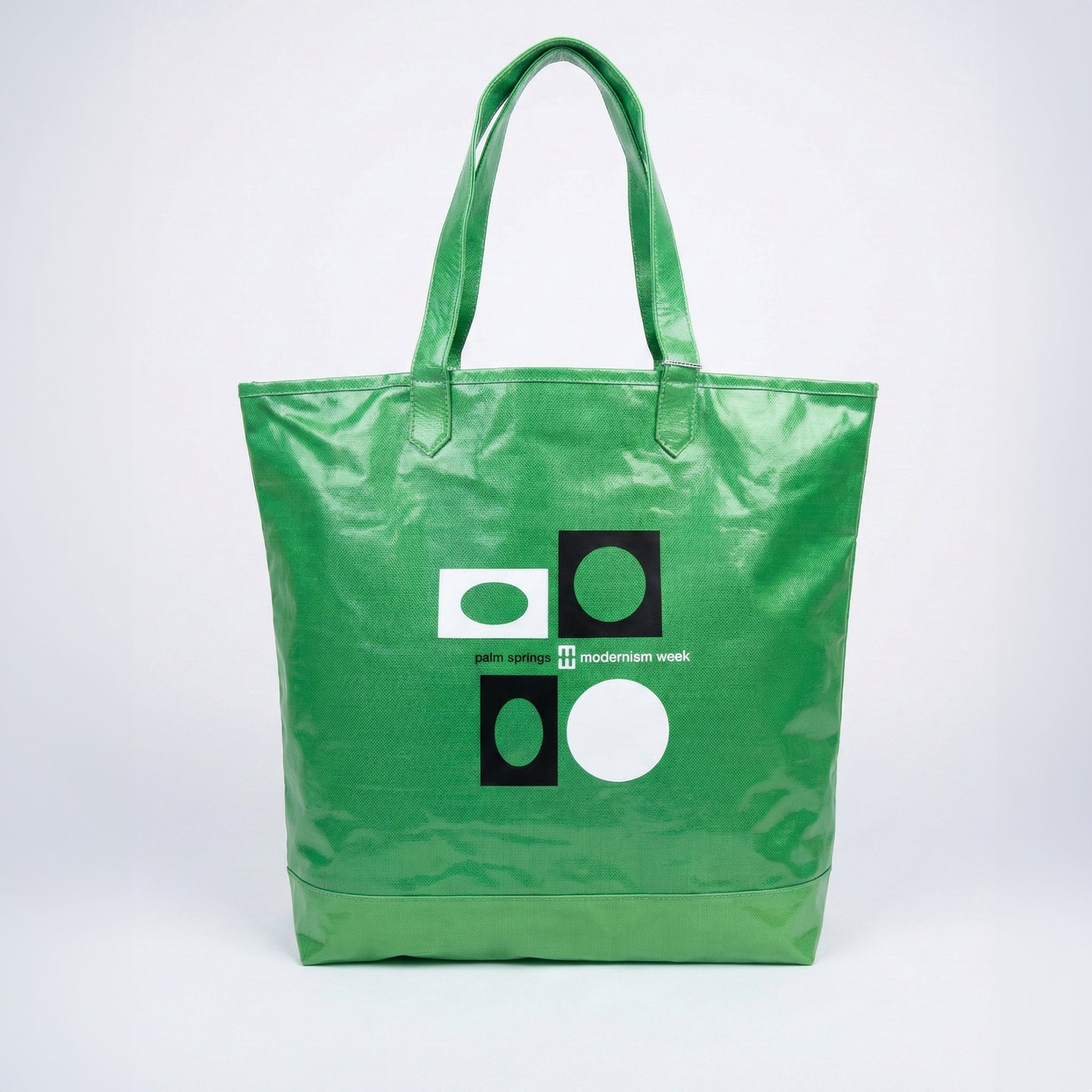 Green tote bag with geometric design and text on a white background