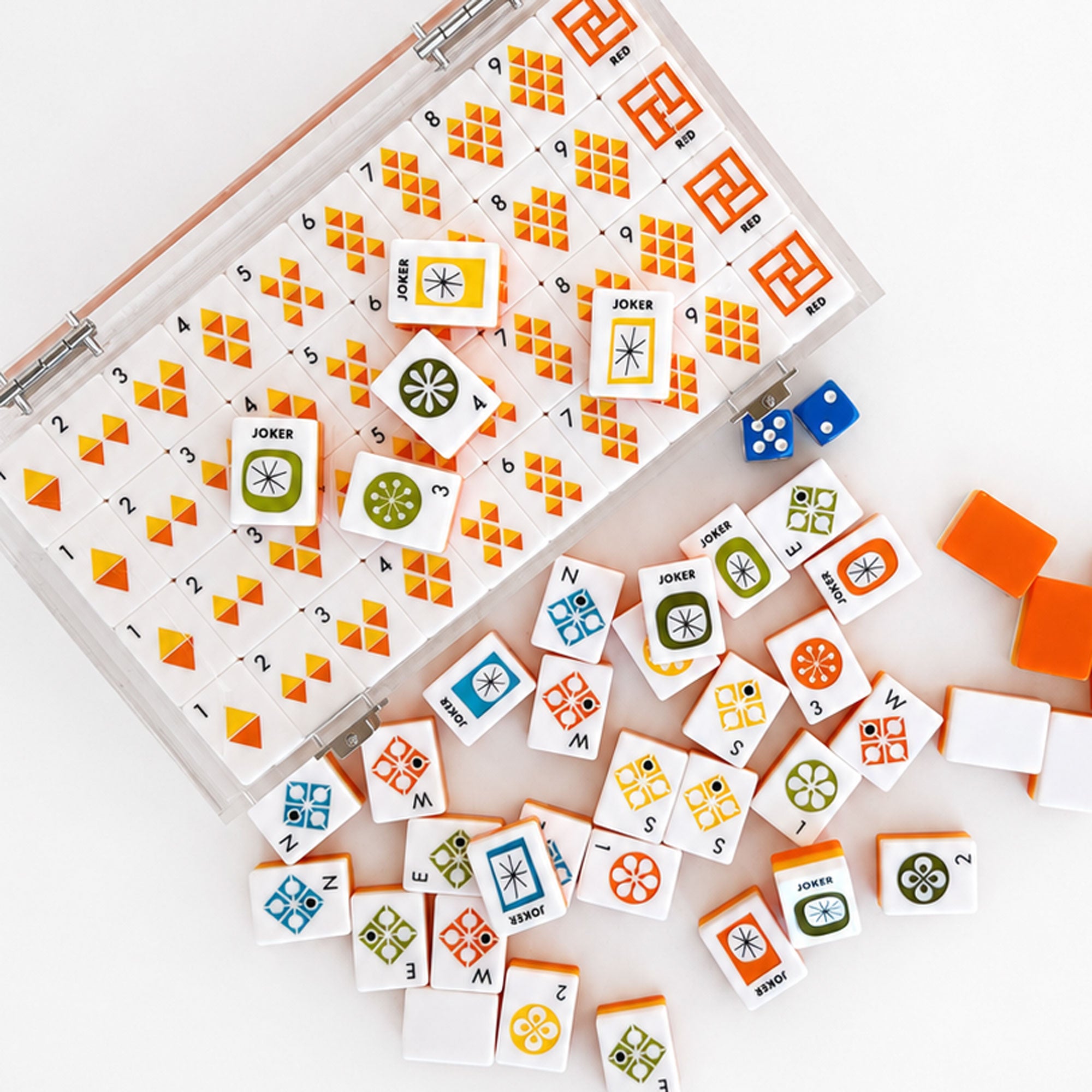 A set of colorful card game blocks and dice displayed on a white surface, with an open clear plastic storage case showing the organized pieces and several loose pieces scattered around.