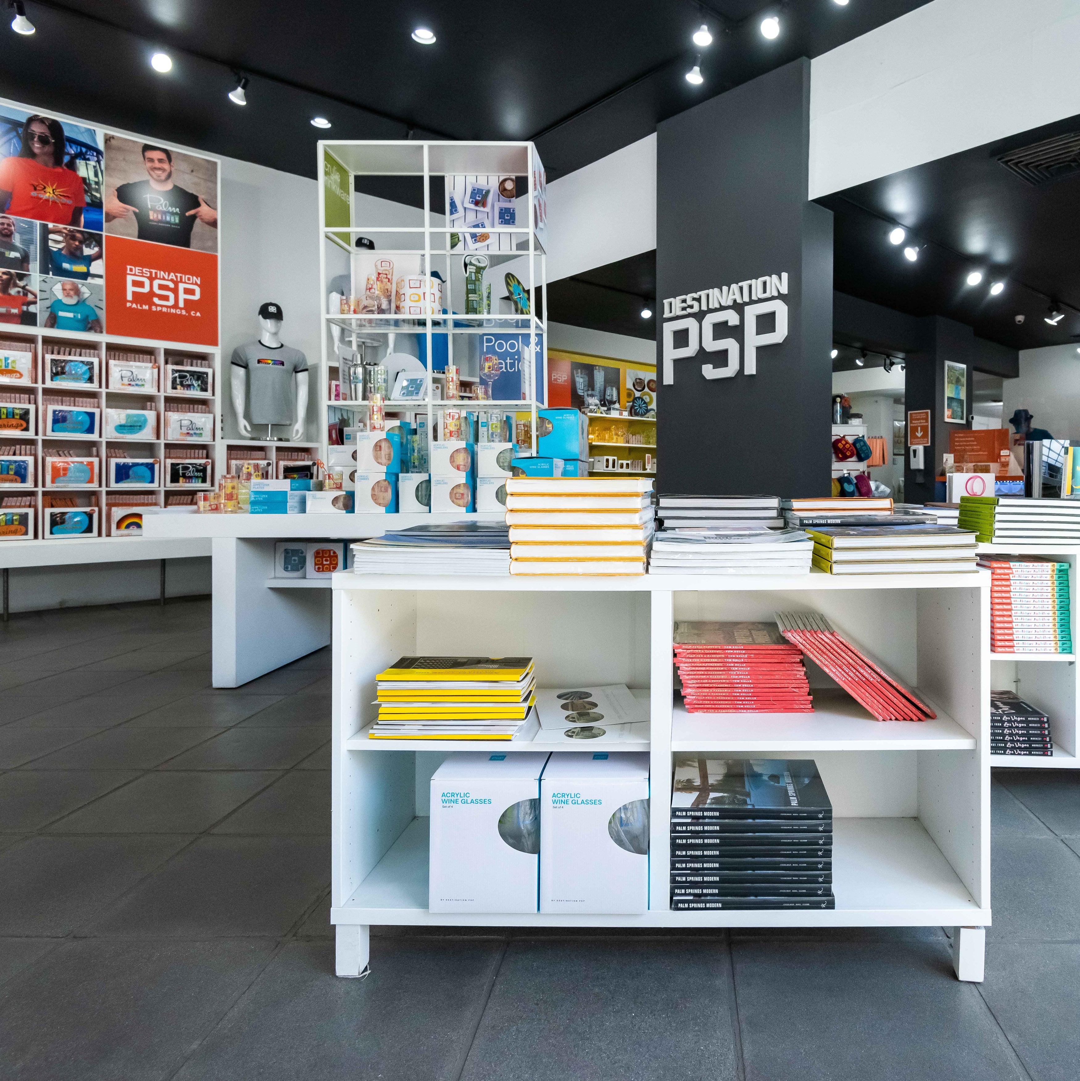 Interior of the Palm Springs retail store, Destination PSP, showcasing shelves brimming with books, t-shirts, and art pieces, complemented by a mannequin displaying store apparel.