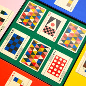 Colorful geometric-patterned playing cards on a green surface
