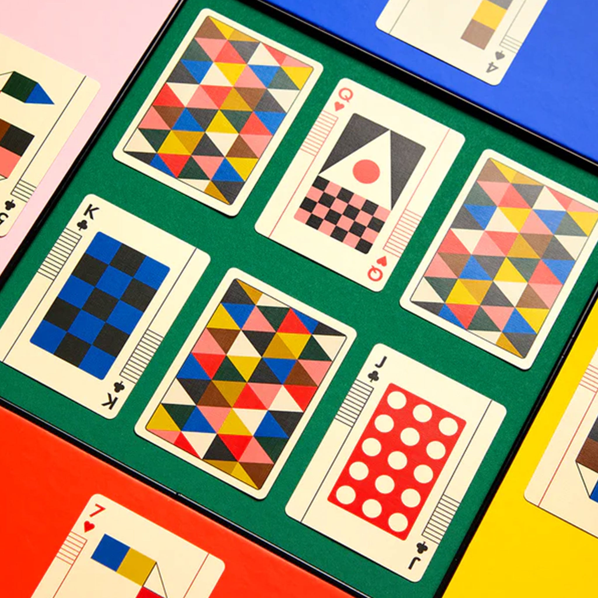Colorful geometric-patterned playing cards on a green surface