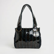 Black handbag with a shiny, reflective surface on a white background