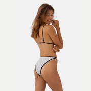 A rear view of a woman wearing a kya reversible swimsuit in wave print.
