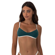 Woman wearing a green bikini top with white straps on a white background