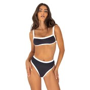 Woman wearing a black and white bikini set on a white background