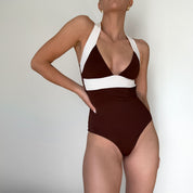 Woman wearing a brown and white swimsuit against a plain background