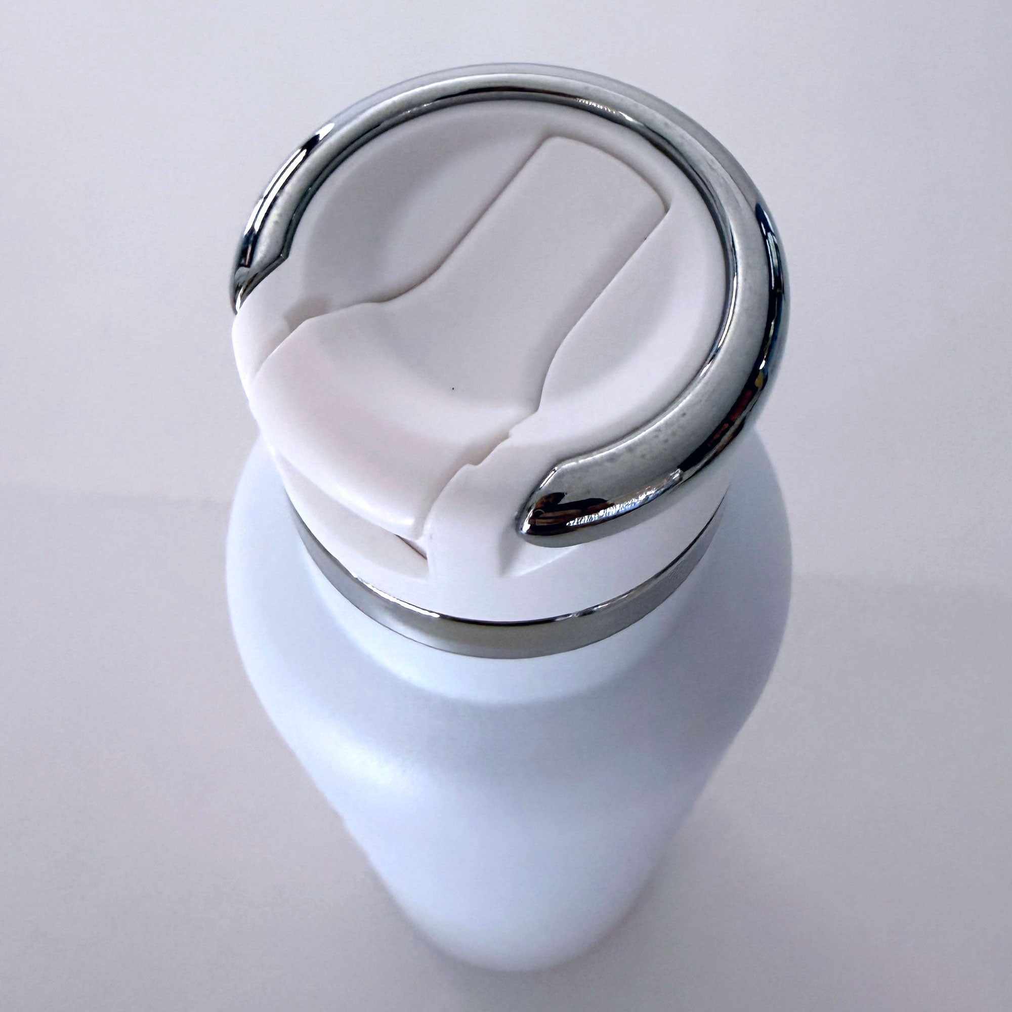White ceramic vase with a silver base on a light gray background