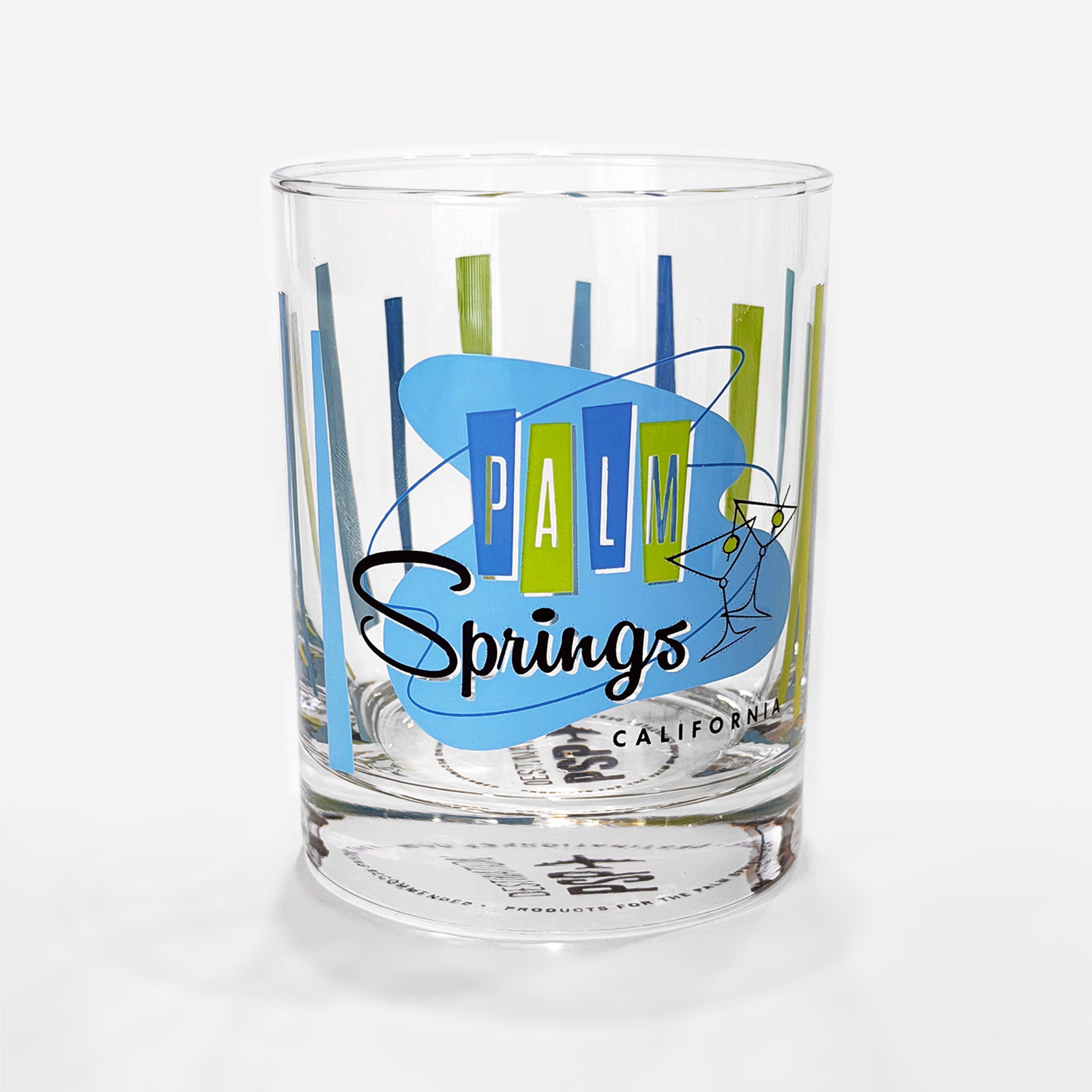 A clear glass tumbler with a retro-style Palm Springs California graphic, featuring blue and green vertical lines, a blue abstract shape, and the words 'PALM Springs' in blue and black, on a light gray background.