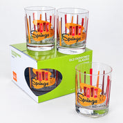 Four clear glass tumblers with a colorful 'Palm Springs California' design, shown with their green and white retail box on a white background.