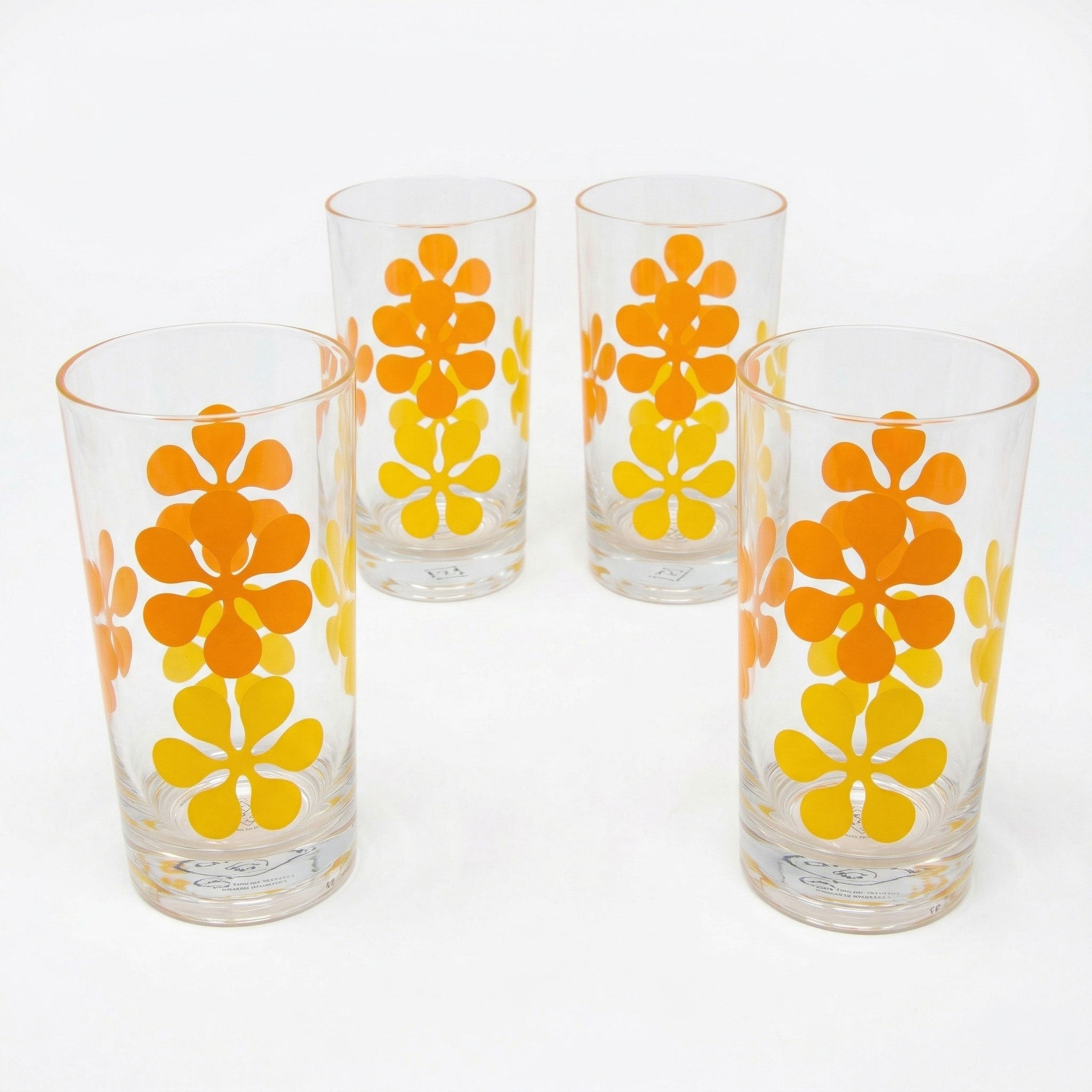 Four glass tumblers with orange and yellow floral patterns on a white background