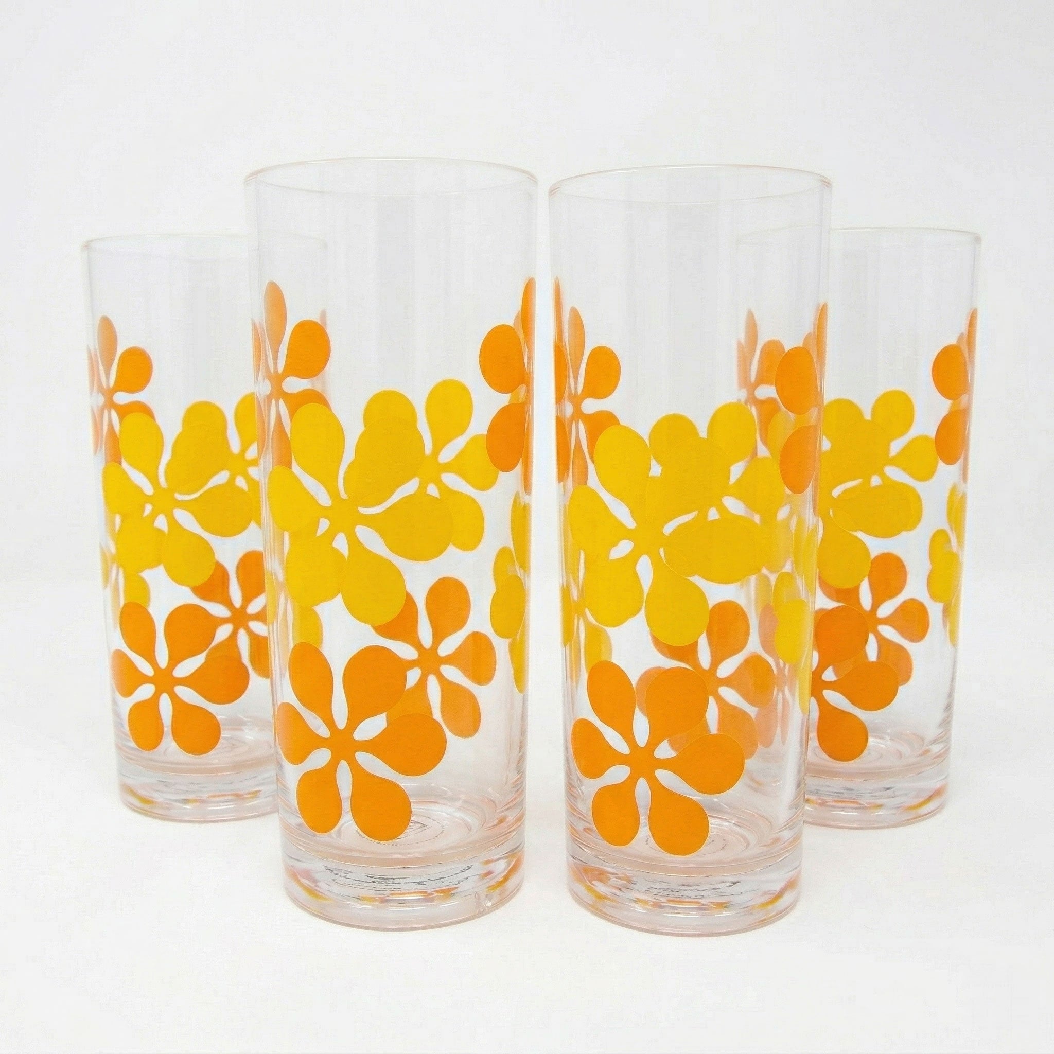 Four glass tumblers with orange floral patterns on a white background