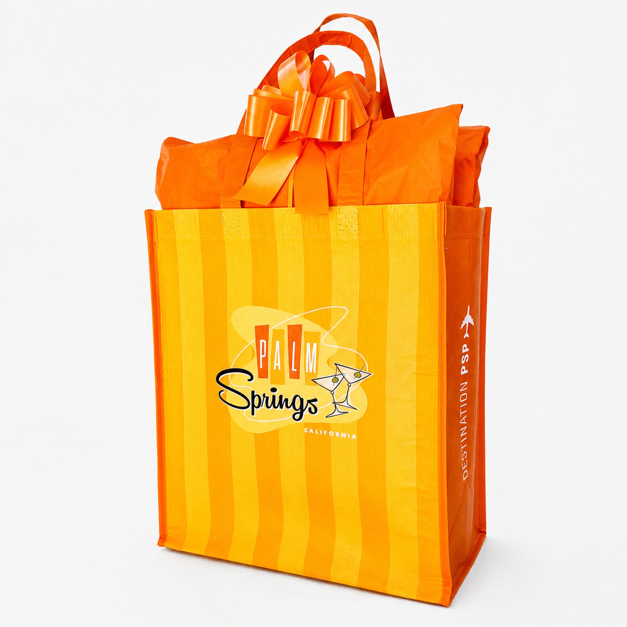 Orange and yellow gift bag with a bow, featuring 'Palm Springs' branding.