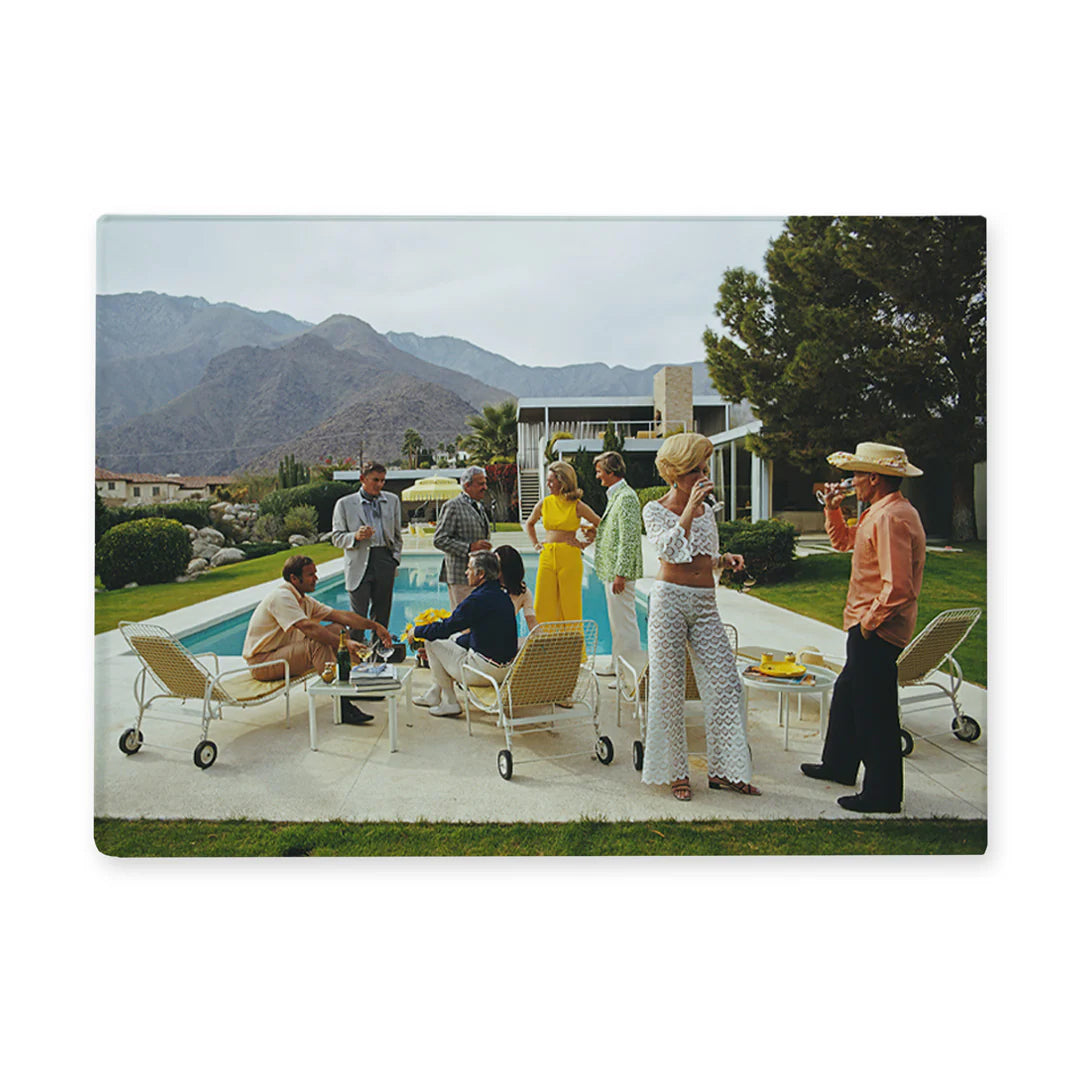 People gathered around a pool with mountains in the background