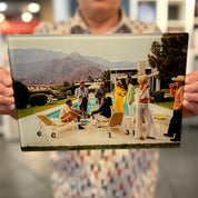 A man holding a cutting board with the poolside gossip photograph printed on it