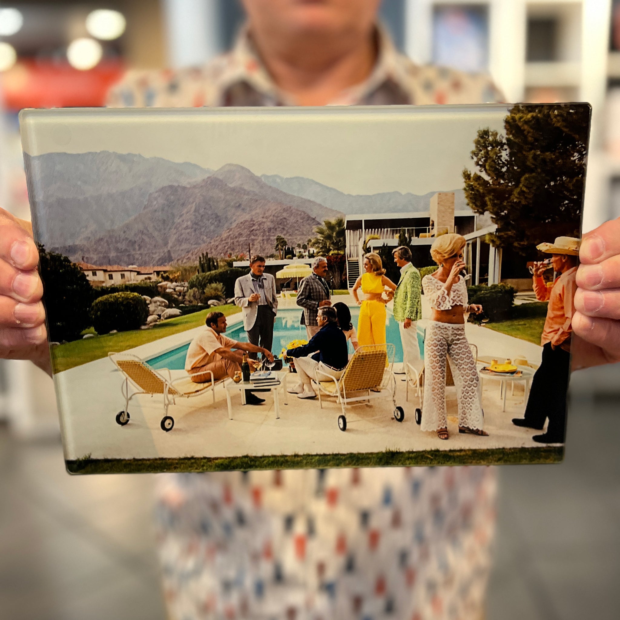 A man holding a cutting board with the poolside gossip photograph printed on it