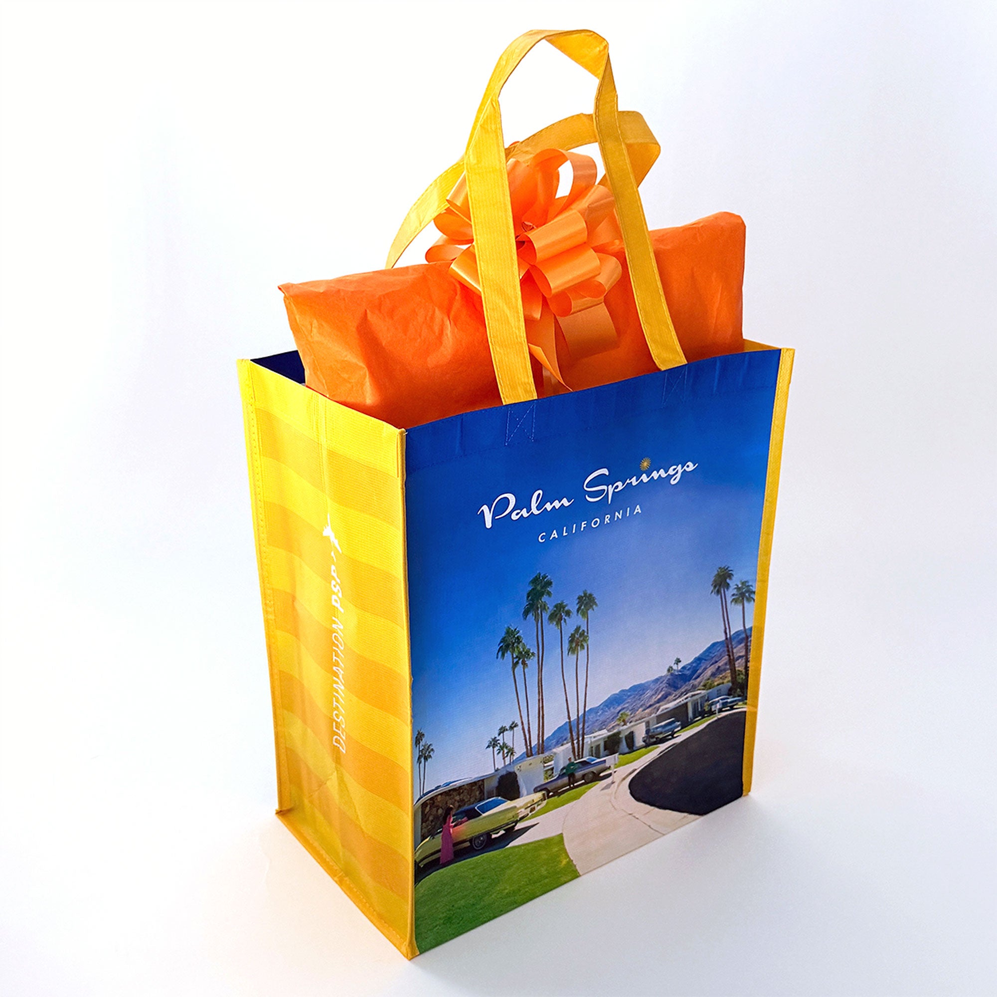 Reusable shopping bag with 'Palm Springs, California' print and orange item inside on a white background